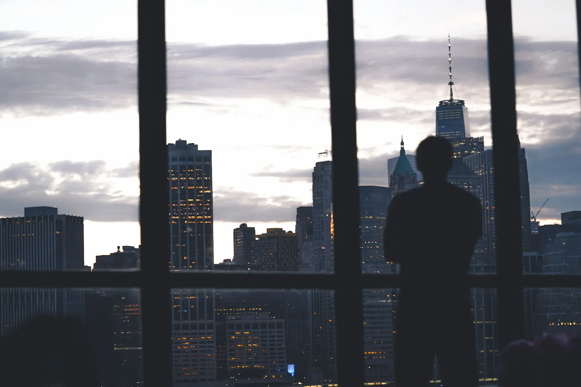 Silhouette eines Privatdetektivs der Berliner Agentur, der aus dem Fenster auf das Panorama einer Geschäftsstadt blickt.